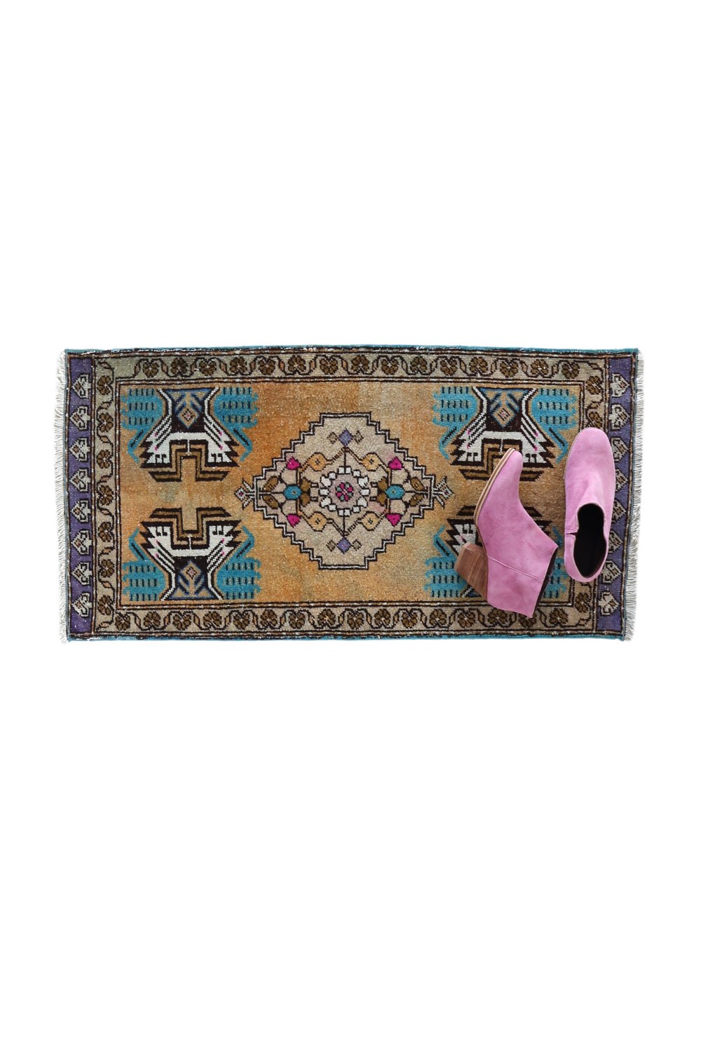 No. 1660 Mini Turkish Vintage Rug - 1'7.5" x 3'2.5" - Canary Lane
A hand woven, vintage rug with a golden peach background and symmetrical geometric design. The central medallion featured intricate patterns in cream, purple, and pink, surrounded by teal and brown accents. Each corner displays bold turquoise and black motifs, and the border includes detailed floral and geometric designs in purple, cream, and brown tones. The rug is neatly finished with fringed edges on both ends. 